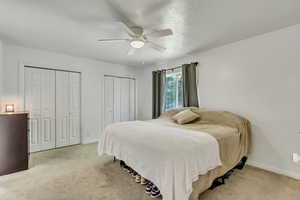 Carpeted bedroom with two closets and ceiling fan