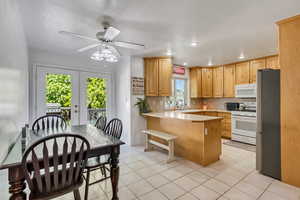 Kitchen with white appliances, a wealth of natural light, kitchen peninsula, and ceiling fan