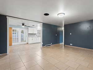 Empty room featuring ceiling fan and light tile patterned flooring