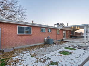 Snow covered house featuring central AC unit and a patio