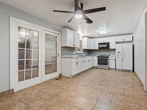 Kitchen featuring decorative backsplash, ceiling fan, electric range, white cabinets, and white fridge with ice dispenser