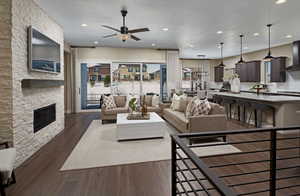 Living room with a fireplace, a textured ceiling, dark hardwood / wood-style floors, and ceiling fan