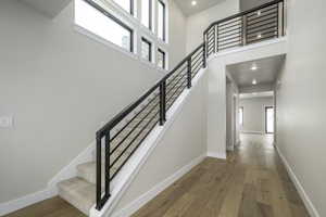 Stairway with a towering ceiling and hardwood / wood-style floors