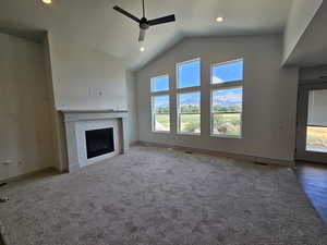 Unfurnished living room featuring carpet, plenty of natural light, ceiling fan, and a tile fireplace