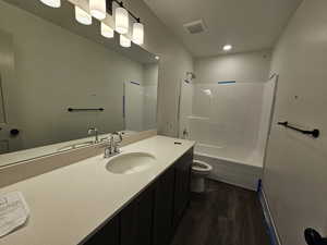 Full bathroom with shower / bathing tub combination, vanity, toilet, and hardwood / wood-style flooring