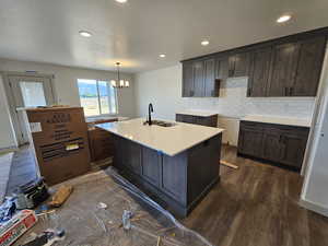 Kitchen with a chandelier, sink, dark hardwood / wood-style floors, decorative backsplash, and dark brown cabinetry