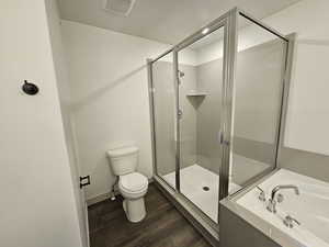 Bathroom featuring toilet, hardwood / wood-style flooring, and shower with separate bathtub