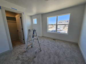 Unfurnished bedroom featuring a closet, a spacious closet, and carpet floors