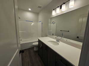 Full bathroom with vanity, toilet, wood-type flooring, and washtub / shower combination