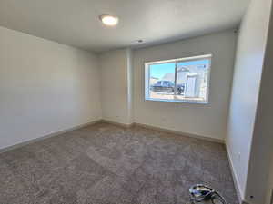 Unfurnished room featuring a textured ceiling and carpet