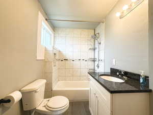 Full bathroom with tile patterned flooring, vanity, toilet, and tiled shower / bath combo