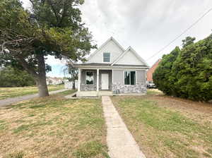 View of front of house with covered porch and a front lawn