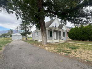 View of front of property with a porch, a garage, an outdoor structure, and a front yard