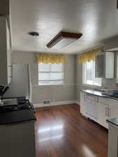 Kitchen with dark wood-type flooring, white appliances, sink, and tasteful backsplash