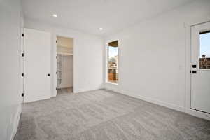 Unfurnished bedroom with a spacious closet, light carpet, and a closet