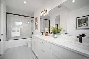 Full bathroom featuring tile patterned flooring, vanity, toilet, and enclosed tub / shower combo