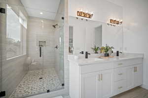 Bathroom with wood-type flooring, vanity, and a shower with shower door