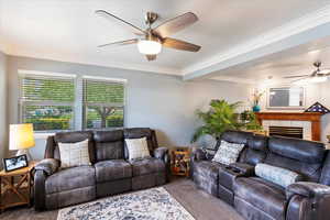 Living room featuring crown molding, carpet flooring, ceiling fan, and a tile fireplace