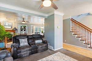 Living room featuring ceiling fan, hardwood / wood-style flooring, and crown molding