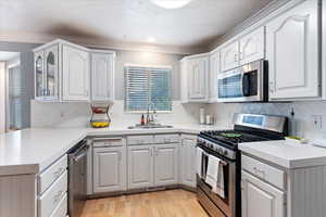 Kitchen featuring sink, appliances with stainless steel finishes, white cabinetry, and light hardwood / wood-style floors