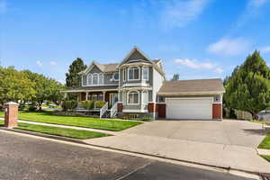 Victorian house featuring a garage, a front yard, and a porch