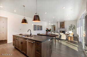 Kitchen with an island with sink, dishwasher, sink, and decorative light fixtures