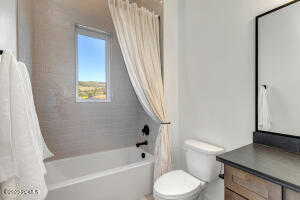 Full bathroom with toilet, shower / tub combo with curtain, and vanity