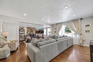 Living room featuring a fireplace, dark wood-type flooring, and a textured ceiling