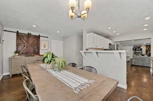 Dining area with dark hardwood / wood-style flooring, a barn door, and a textured ceiling