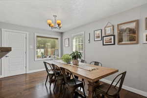 Dining room featuring a textured ceiling, dark hardwood / wood-style floors, and a chandelier