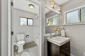 Full bathroom featuring hardwood / wood-style floors, tiled shower / bath, toilet, and vanity