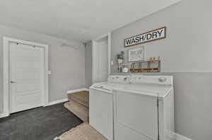 Laundry room with a textured ceiling, washer and clothes dryer, and carpet