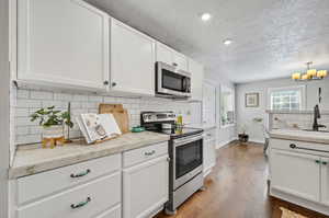 Kitchen featuring white cabinets, decorative backsplash, stainless steel appliances, and dark hardwood / wood-style floors