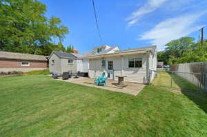 Back of house with a lawn and a patio area