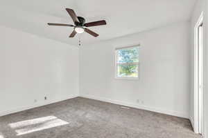 Carpeted empty room featuring ceiling fan