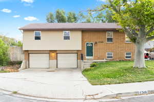 Raised ranch featuring a garage and a front lawn