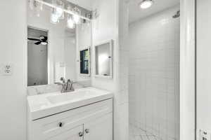 Bathroom with vanity, ceiling fan, and tiled shower