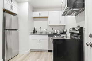 Kitchen featuring light hardwood / wood-style flooring, sink, appliances with stainless steel finishes, and white cabinets