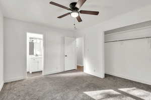 Unfurnished bedroom featuring ceiling fan, carpet floors, a closet, and ensuite bath