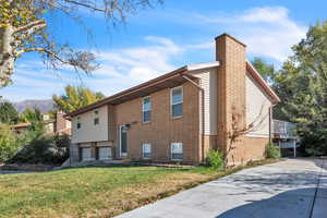 View of side of home with a mountain view and a lawn