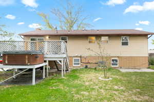 Back of property featuring a wooden deck and a yard