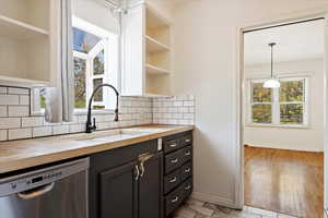 Kitchen featuring light wood-type flooring, backsplash, dishwasher, and wood counters