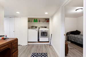 Washroom with separate washer and dryer, light wood-type flooring, and a textured ceiling