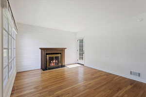 Unfurnished living room with a tiled fireplace and wood-type flooring