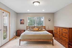 Bedroom with light colored carpet, multiple windows, and access to outside