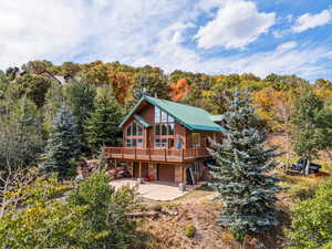 Back of house with a wooden deck and a patio