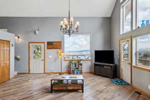 Living room featuring high vaulted ceiling, a notable chandelier, and light hardwood / wood-style flooring