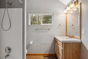 Bathroom with vanity, toilet, walk in shower, and lofted ceiling