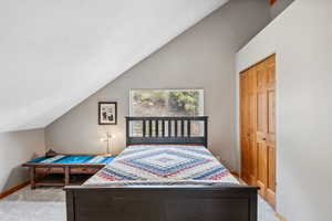 Bedroom featuring vaulted ceiling, a closet, and light carpet