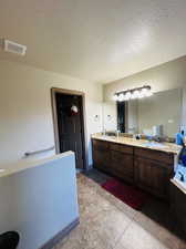 Bathroom featuring tile patterned floors, a textured ceiling, and vanity